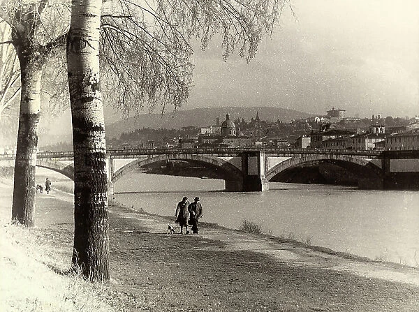 Couple walking along the Arno at the Cascine, on the background Ponte alla Vittoria in Florence