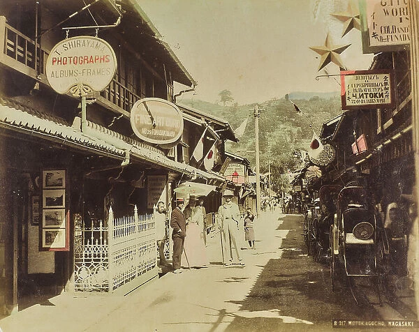 A street in Nagasaki with Western people, parked rickshaws and photo shop 'T. Shirayama', Japan