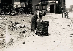 Images Dated 24th May 2011: Deserted street of New York with a young barefooted boy dressed in rags rummaging in a trash can