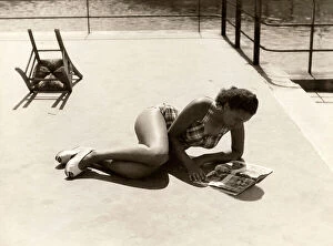 Images Dated 21st October 2011: A girl wears a swimming suit while reading a magazine and tanning