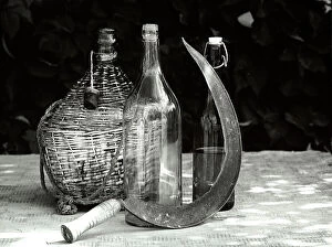 Images Dated 11th April 2011: Still life with a demijohn, two bottles and a scythe on a table