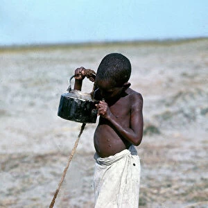 Images Dated 17th November 2009: Lower Juba. Children quench their thirst at a well from an old tea kettle