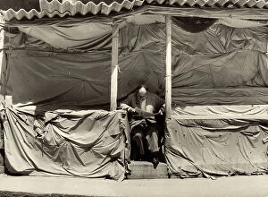 Images Dated 15th April 2011: Man reads a newspaper while sitting at his, closed, market stall
