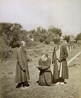 Images Dated 16th May 2011: An old man kneeling on the ground asking for and receiving alms from two passersby