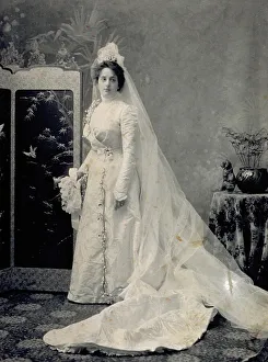 Portrait dune jeune femme en robe de mariée avec voile long et fleurs.