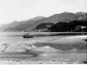 Images Dated 12th March 2010: Beyond the rocky shore of Lake Como is ferry. On the horizon is the panorama of Bellagio with