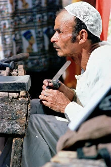 Images Dated 13th October 2011: Upper Egypt, Esna, a cobbler works with his dinner on the road