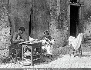 Images Dated 28th July 2011: View of a city street typical of Rome and its outskirts. A cobbler does his work while a woman