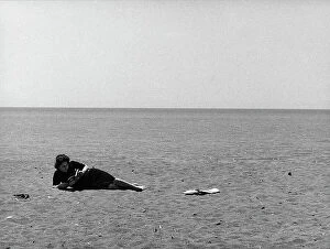 Images Dated 11th April 2011: Woman reads stretched out on a beach
